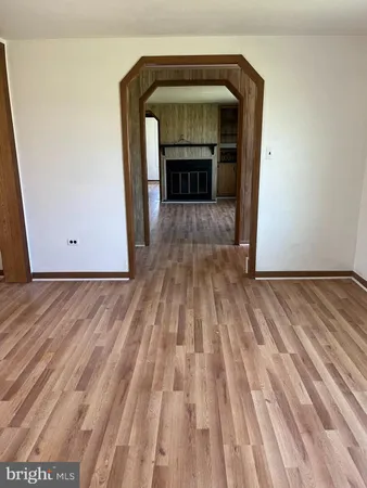 a view of empty room with wooden floor and fireplace