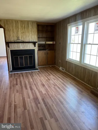 an empty room with wooden floor a fireplace and windows