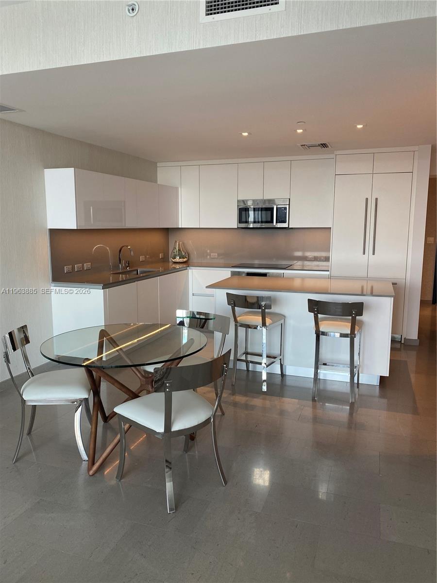 88 Southwest 7th Street, Unit 1904 Miami, FL 33130 - Photo 11 of 33 a kitchen with a table chairs a sink dishwasher window and cabinets