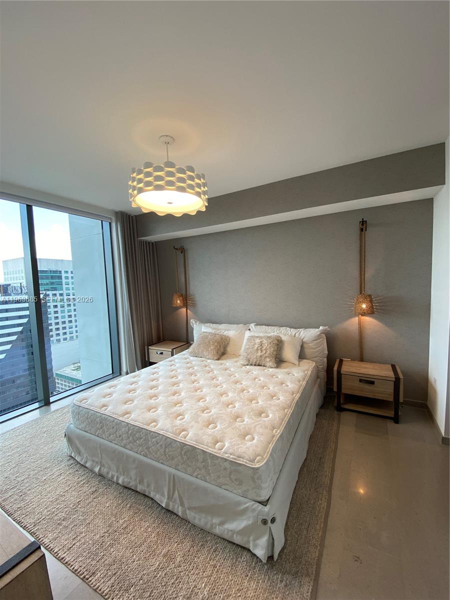 88 Southwest 7th Street, Unit 1904 Miami, FL 33130 - Photo 23 of 33 a bedroom with a bed and a chandelier