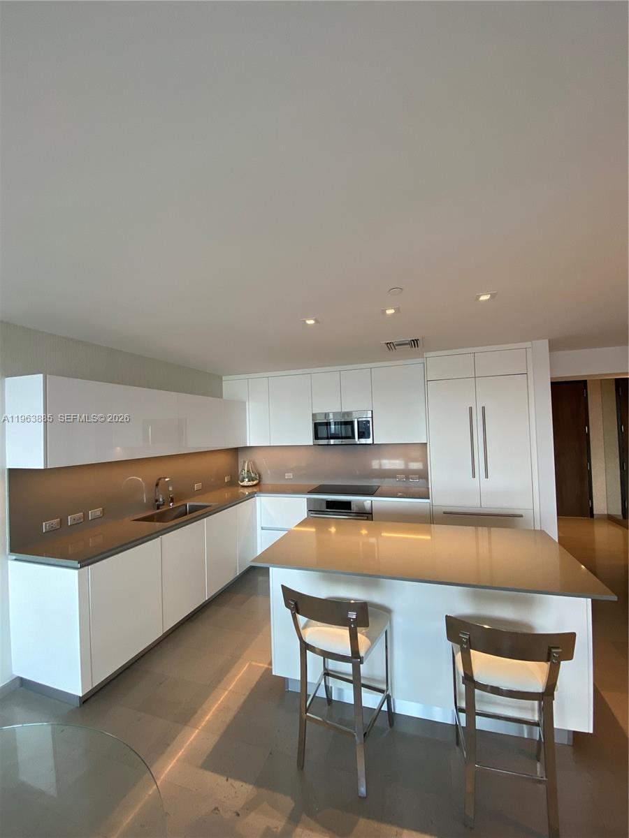 88 Southwest 7th Street, Unit 1904 Miami, FL 33130 - Photo 5 of 33 a kitchen with stainless steel appliances granite countertop a table chairs sink and cabinets