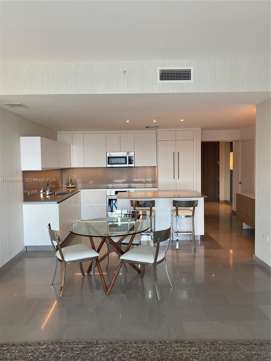 88 Southwest 7th Street, Unit 1904 Miami, FL 33130 - Photo 7 of 33 a living room with stainless steel appliances kitchen island granite countertop a stove a sink a dining table and chairs with wooden floor