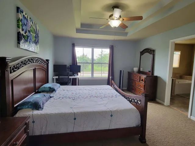 a bedroom with a bed dresser and a chandelier