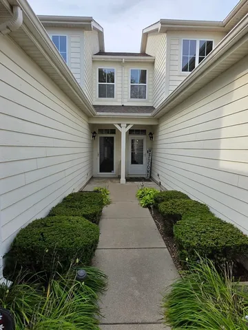 a view of a white house with a small yard and plants