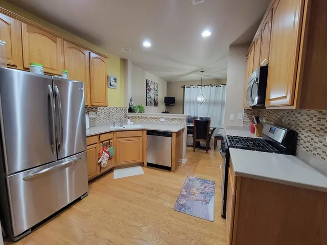 a kitchen with stainless steel appliances granite countertop a refrigerator a stove a sink and a refrigerator