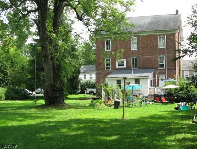 a view of an house with backyard and a tree