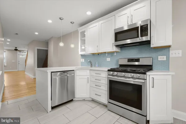a kitchen with stainless steel appliances granite countertop a stove top oven a sink dishwasher and a refrigerator with wooden cabinets