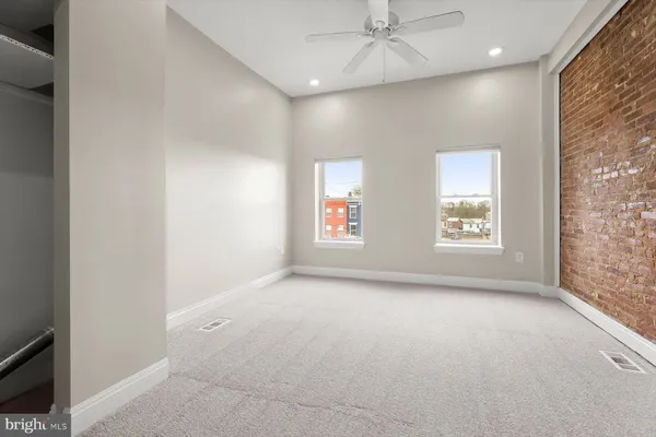 an empty room with windows and fan