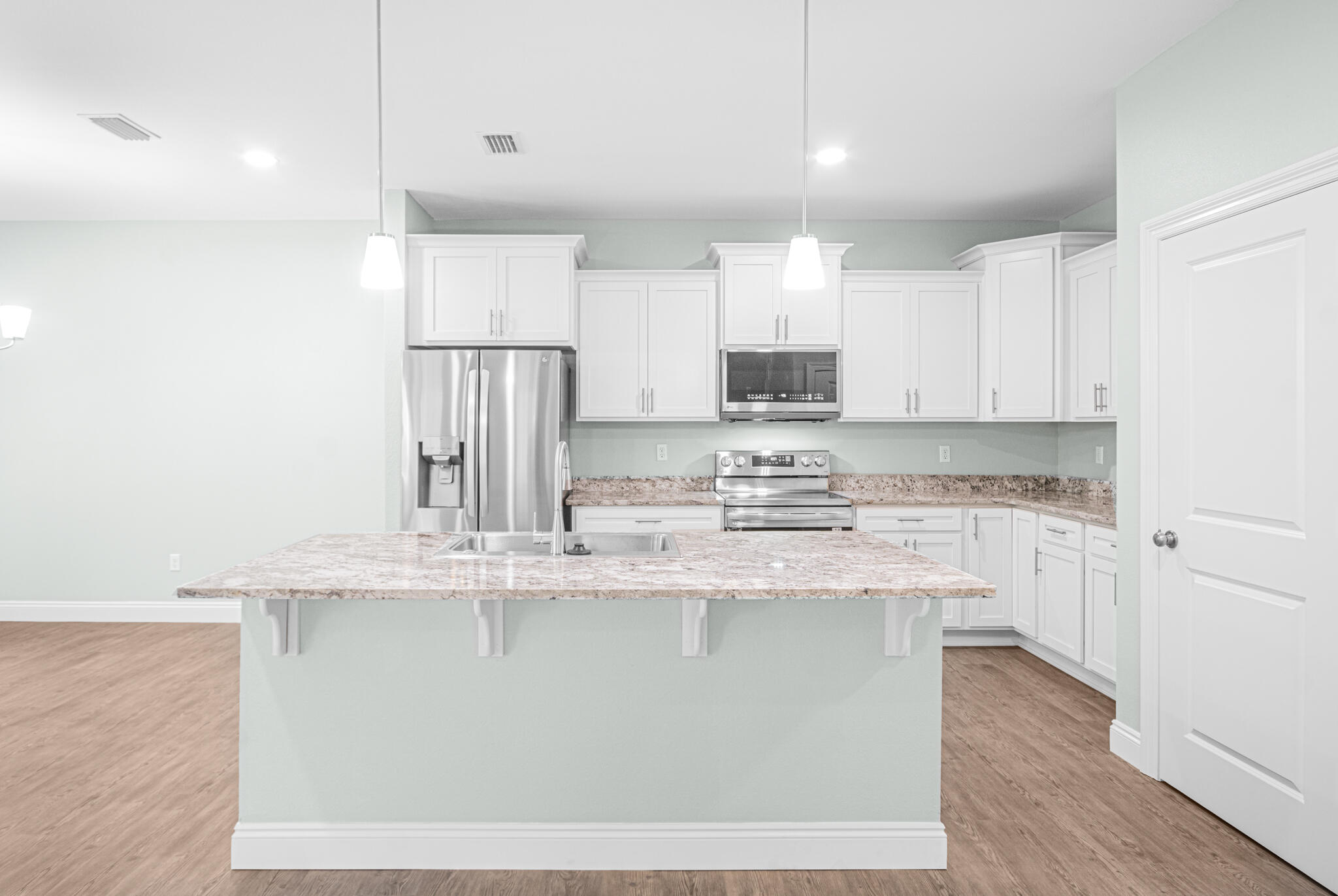 169 Johnson Court Crestview, FL 32536 - Photo 10 of 30 a kitchen with stainless steel appliances granite countertop a sink a stove a refrigerator and white cabinets with wooden floor