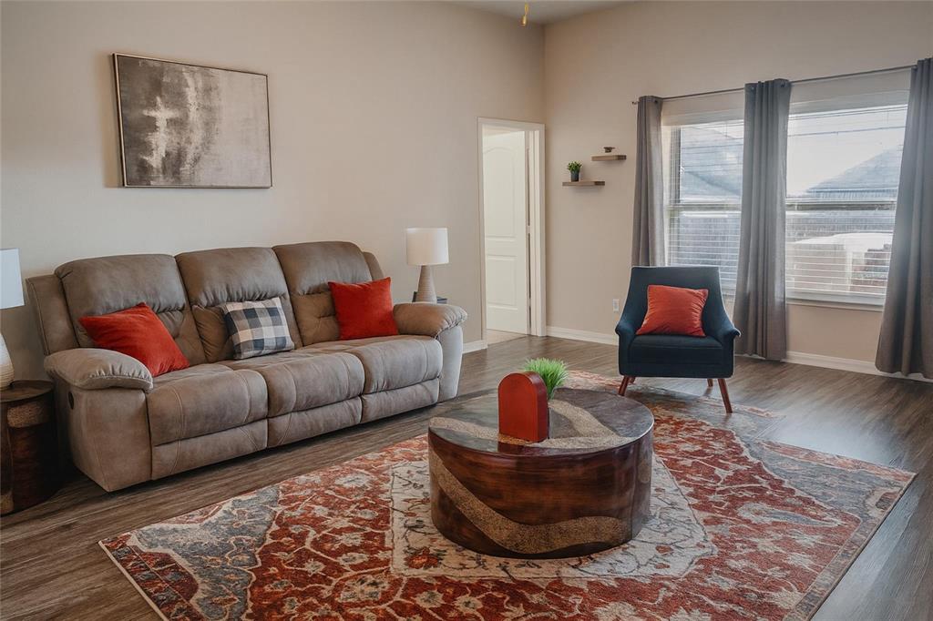 1837 Rialto Lane Crowley, TX 76036 - Photo 17 of 19 Spacious living area featuring wood-finish flooring, ample natural light from multiple windows, neutral wall tones, and a door frame providing access to another room