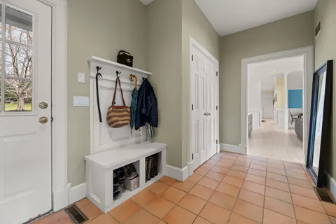 a view of a hallway to a livingroom with wooden floor and furniture