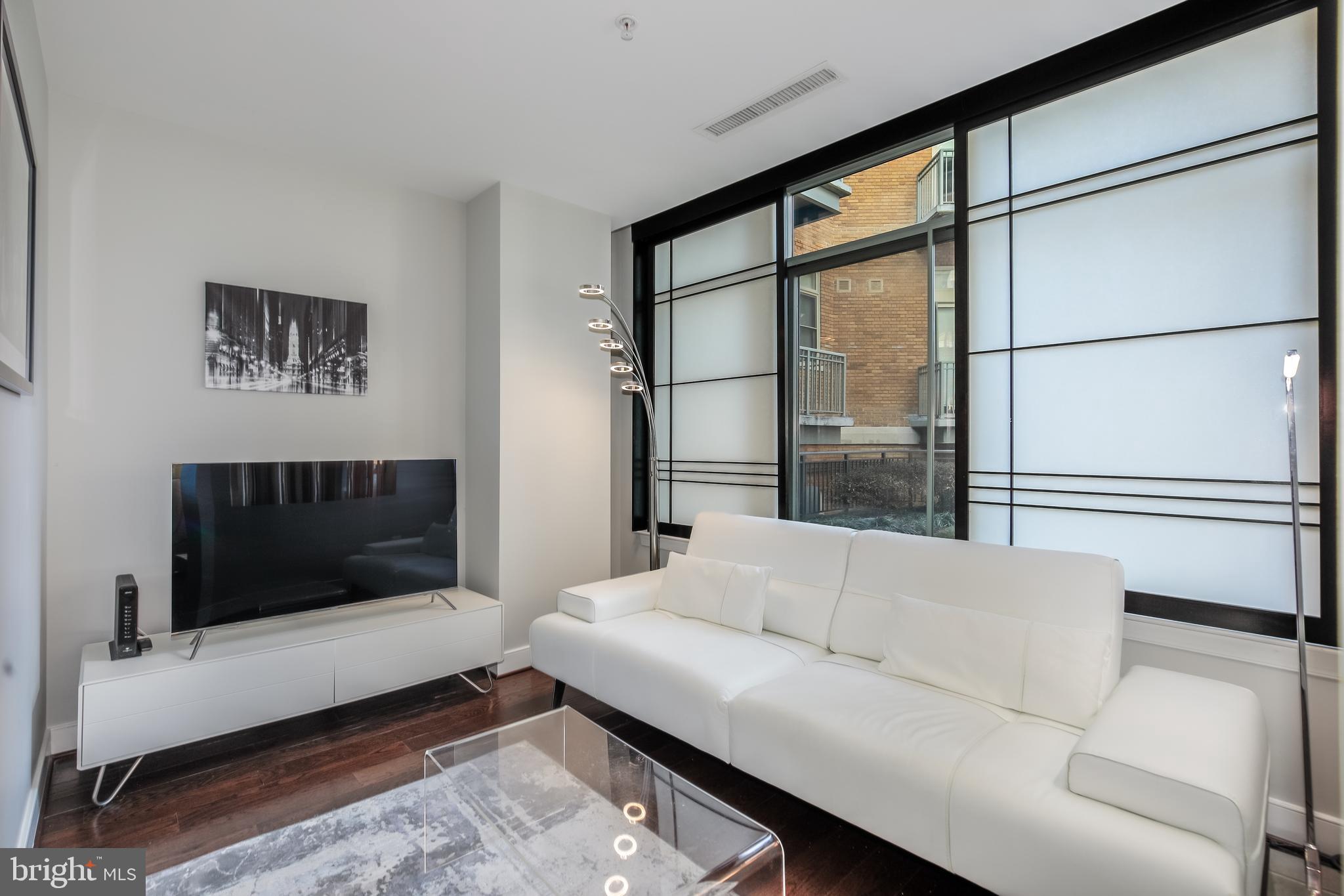 2425 L Street Northwest, Unit 211 Washington, DC 20037 - Photo 12 of 43 a living room with furniture and a flat screen tv