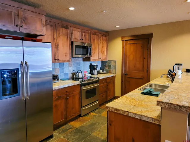 a kitchen with stainless steel appliances granite countertop a refrigerator a stove top oven a sink and dishwasher