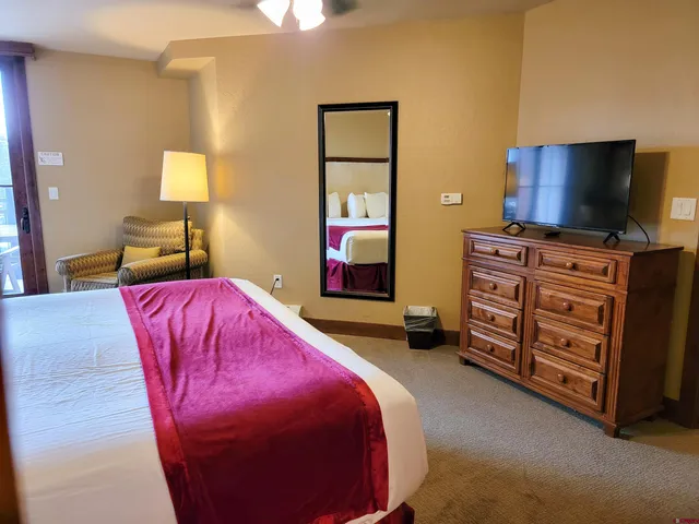 a bedroom with bed and a flat tv screen on dresser