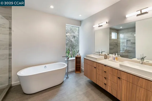 a bathroom with a tub double sink shower and mirror