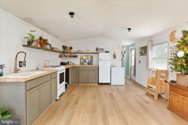 a kitchen with a sink a refrigerator and wooden floor
