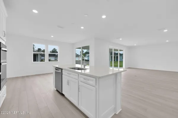 a view of kitchen with kitchen island a sink wooden floor and a refrigerator