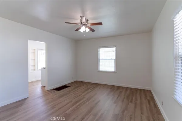 an empty room with wooden floor fan and windows