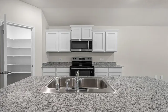 a kitchen with granite countertop white cabinets and a sink