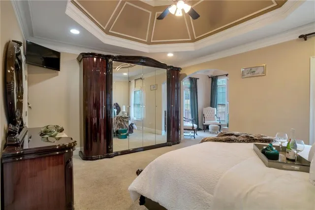 a bedroom with a bed a chandelier and a flat screen tv