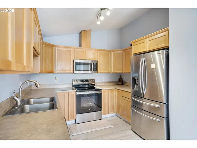 a kitchen with stainless steel appliances granite countertop a refrigerator sink and stove