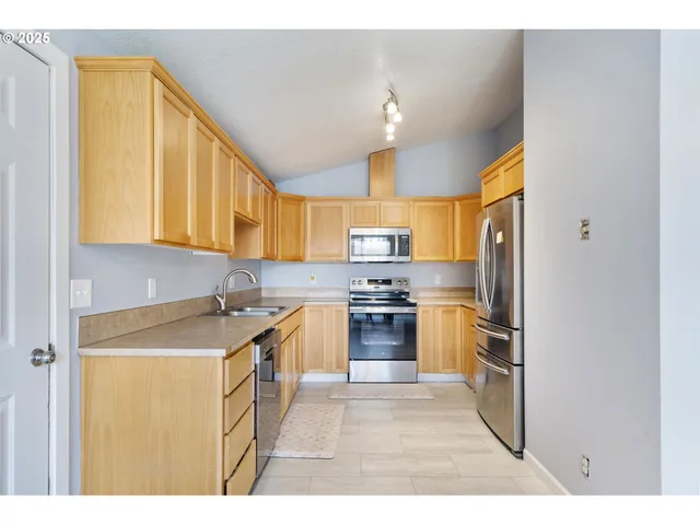 a kitchen with stainless steel appliances granite countertop a sink a stove and a refrigerator