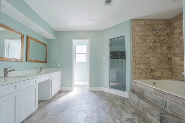 a spacious bathroom with a bathtub sink mirror and shower
