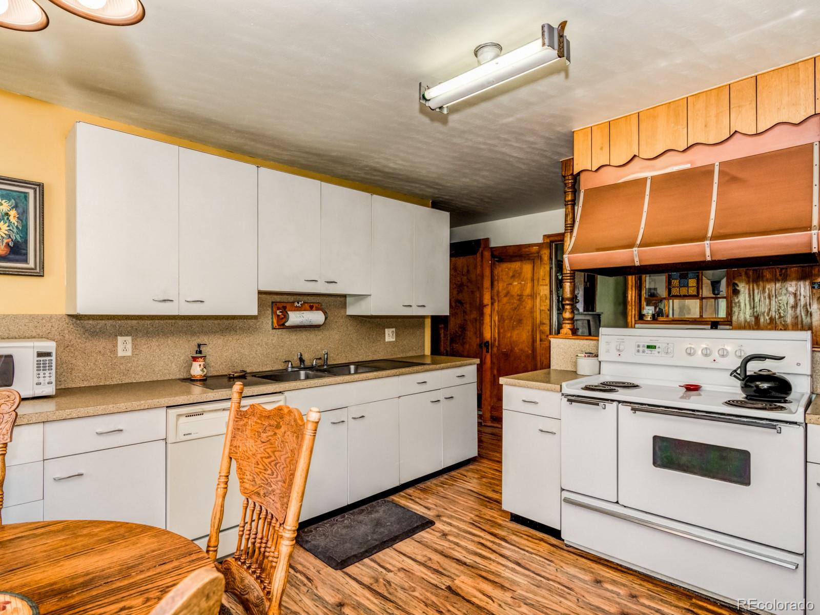 9695 Jones Road Franktown, CO 80116 - Photo 12 of 40 a kitchen with stainless steel appliances granite countertop a stove a sink dishwasher and white cabinets with wooden floor