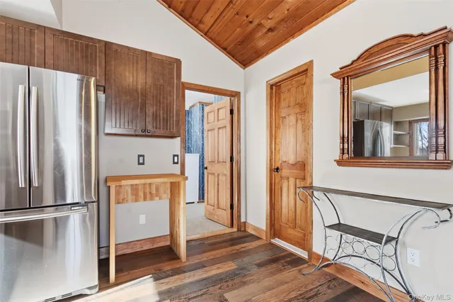 an empty room with wooden floor and a kitchen view