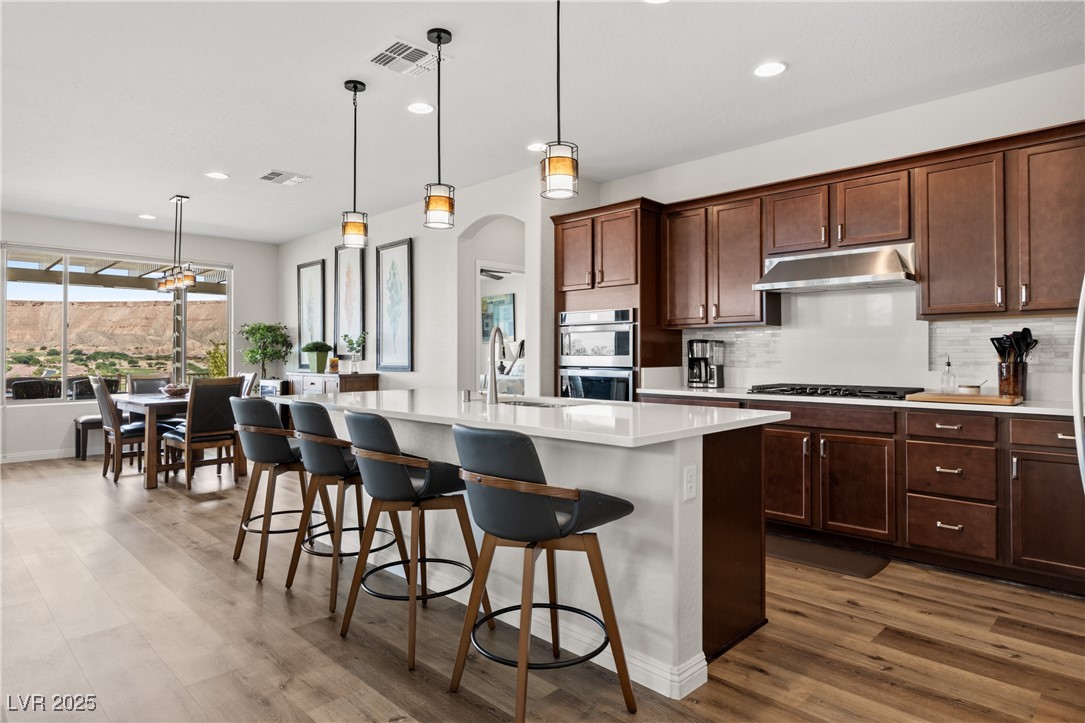 1221 Tortoise Ridge Mesquite, NV 89034 - Photo 22 of 56 Kitchen featuring backsplash, pendant lighting, recessed lighting, an island with sink, and dark wood-style floors
