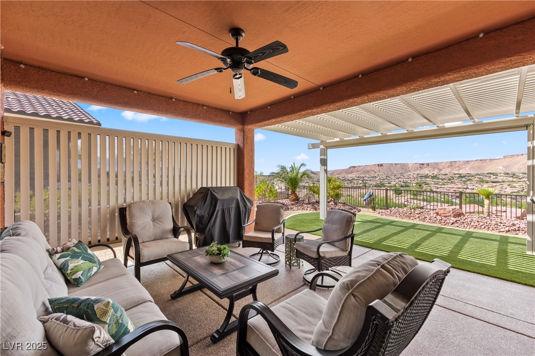 1221 Tortoise Ridge Mesquite, NV 89034 - Photo 33 of 56 Fenced backyard with an outdoor hangout area, a pergola, grilling area, ceiling fan, and a mountain view