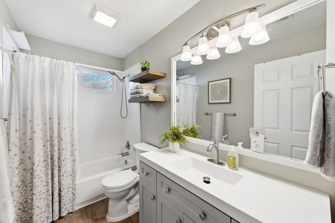 4615 Munson Street Austin, TX 78721 - Photo 21 of 27 Bathroom with shower / bath combination with curtain, vanity, and dark wood finished floors