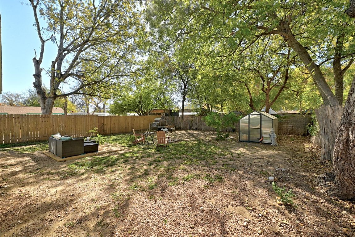 4615 Munson Street Austin, TX 78721 - Photo 24 of 27 Fenced backyard with a greenhouse, an outbuilding, and an outdoor hangout area