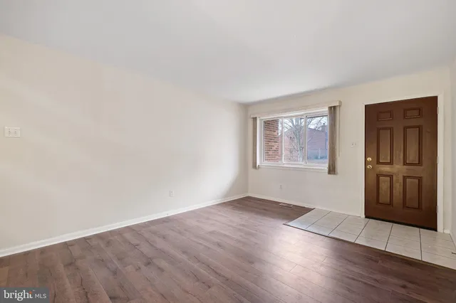 a view of a hallway with wooden floor and a kitchen
