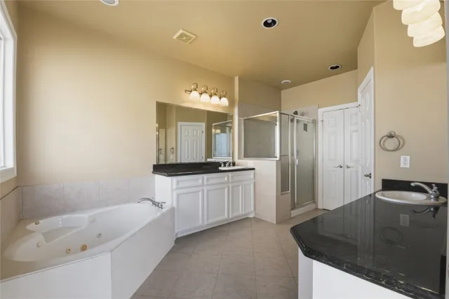 a bathroom with a granite countertop sink a mirror a bathtub and shower