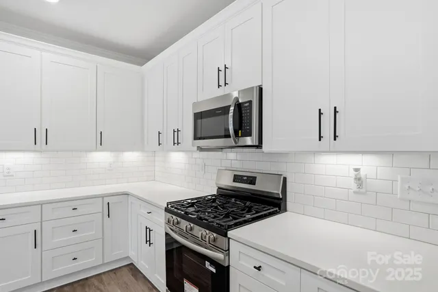 a kitchen with stainless steel appliances granite countertop a sink a stove and a wooden floors