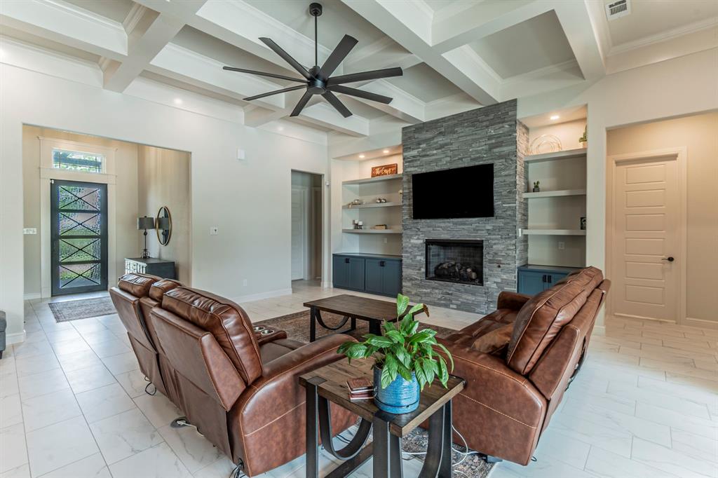 150 Las Brisas Drive Decatur, TX 76234 - Photo 7 of 33 Living area featuring a stone fireplace, ceiling fan, coffered ceiling, built in shelves, and crown molding