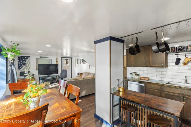 a kitchen with stainless steel appliances granite countertop a stove top oven a sink dishwasher a dining table and chairs with wooden floor