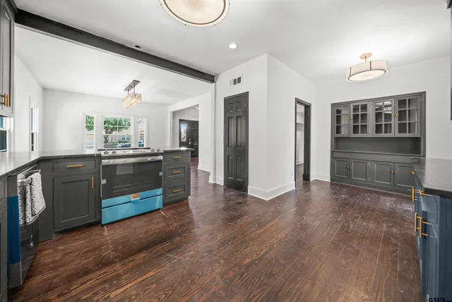 a view of kitchen and empty room with wooden floor