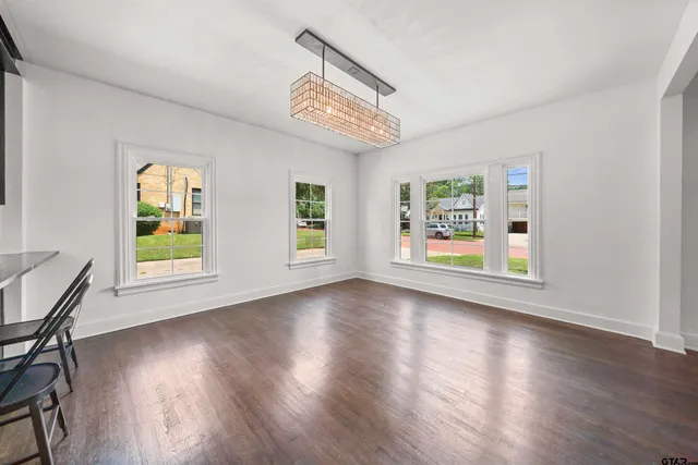 a view of an empty room with window and wooden floor