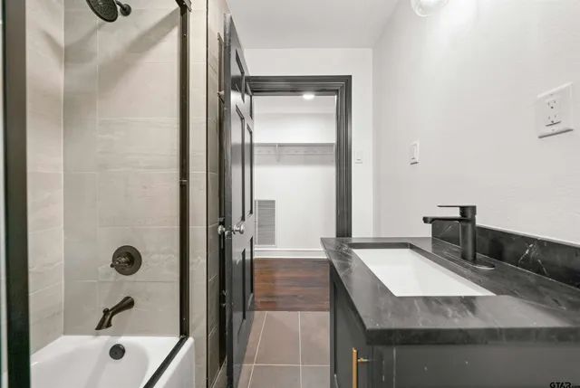 a bathroom with a granite countertop sink a mirror and shower
