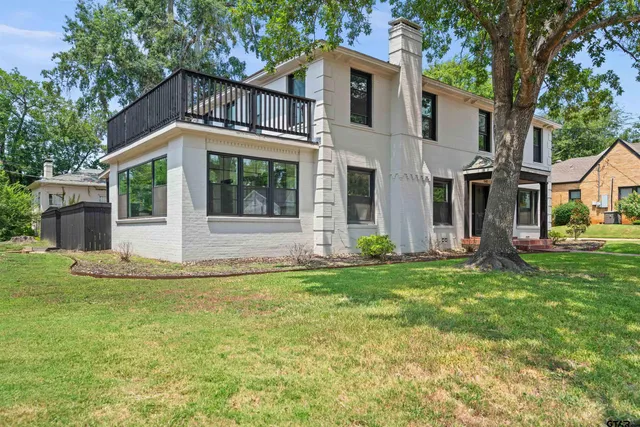 a view of a white house with a big yard and large trees