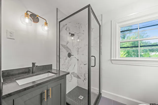 a bathroom with a granite countertop sink a mirror a shower and a vanity
