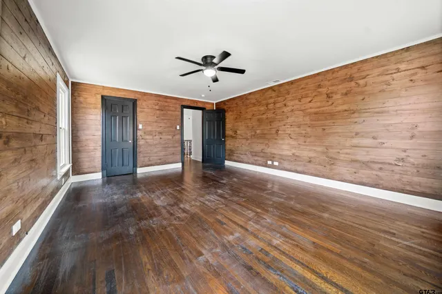 a view of a big room with wooden floor ceiling fan and windows