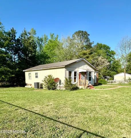 a big white house with a yard and trees in the background