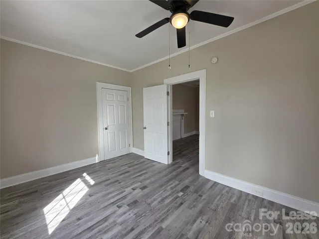 an empty room with wooden floor fan and windows