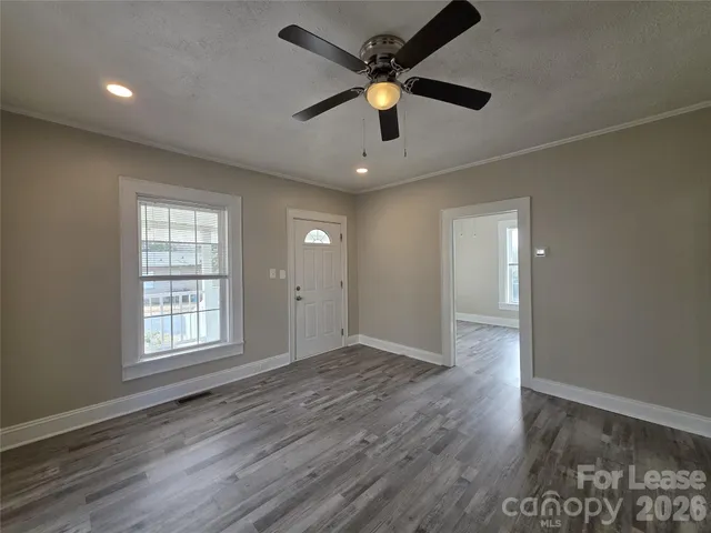 an empty room with wooden floor and windows