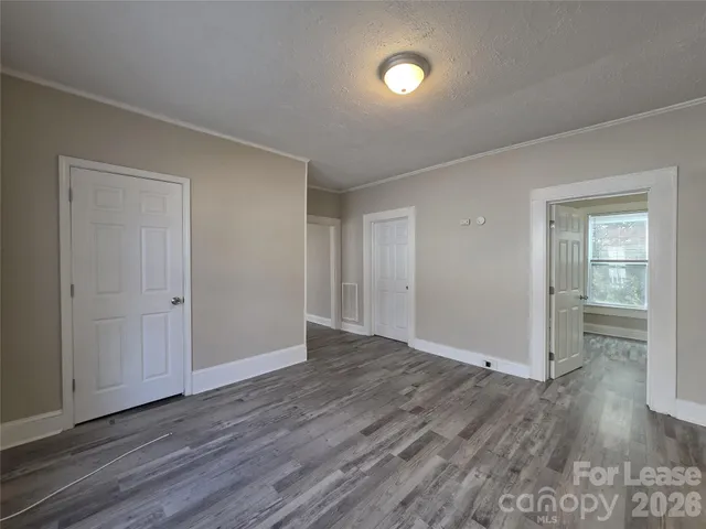 a view of an empty room with wooden floor and closet