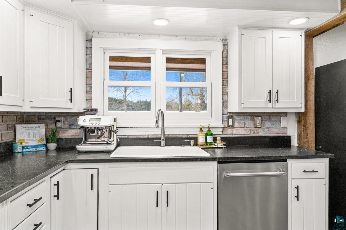 27 West Stark Road Esko, MN 55733 - Photo 11 of 47 Kitchen with white cabinetry, stainless steel dishwasher, backsplash, and freestanding refrigerator