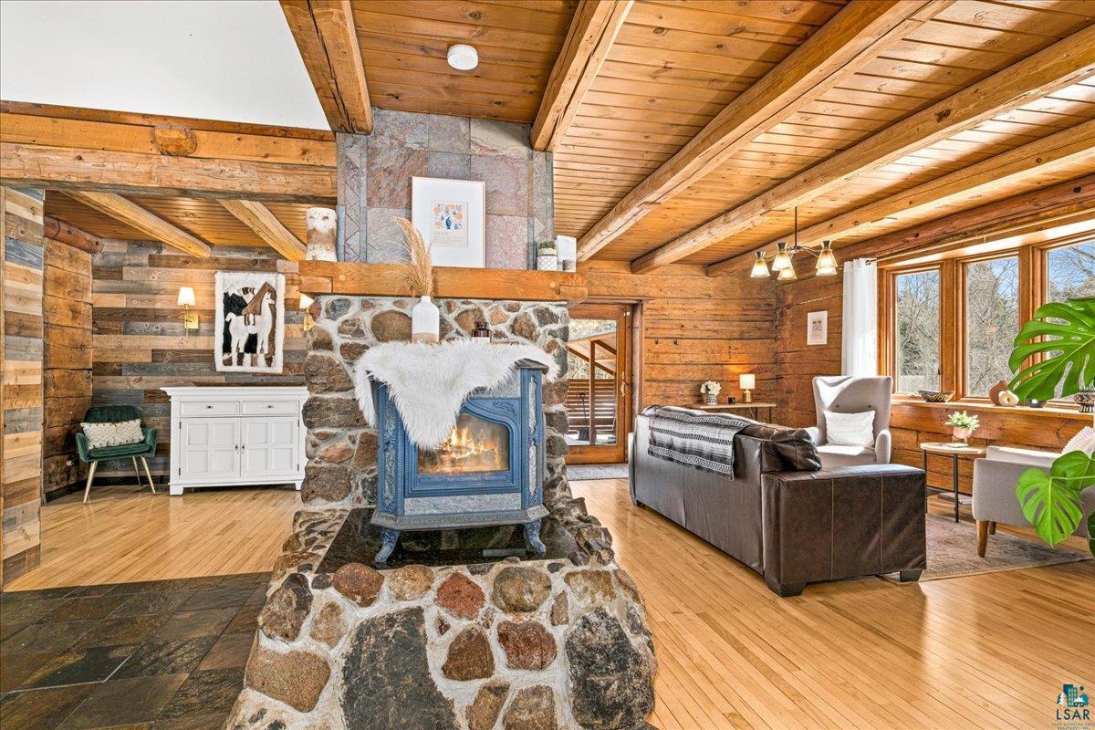 27 West Stark Road Esko, MN 55733 - Photo 15 of 47 Living area featuring a wooden ceiling with exposed beams, wooden walls, light wood-style floors, and a wood stove